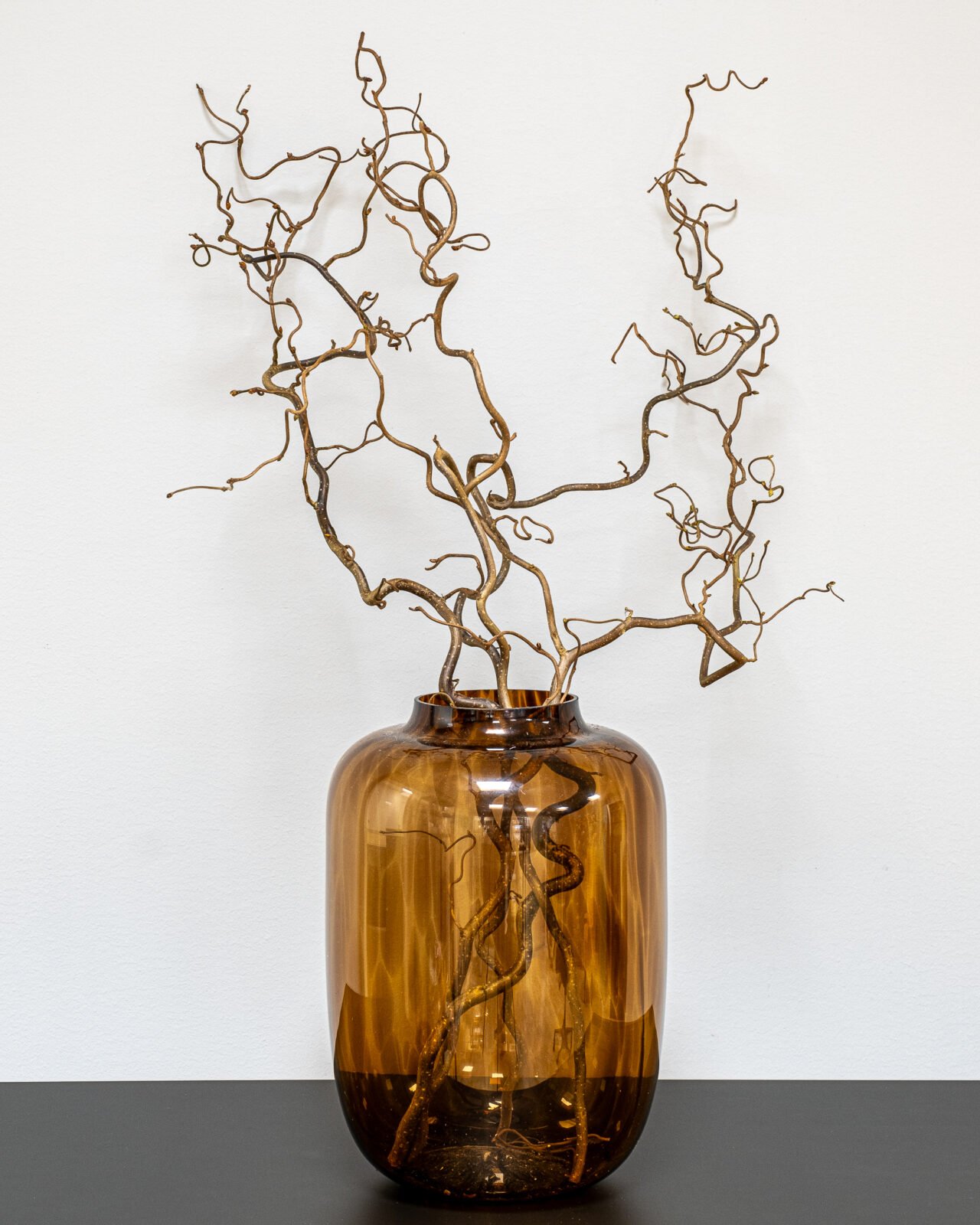 Elegante snoede troldhassel grene i en gulvvase skaber en moderne nordisk indretningsstil.